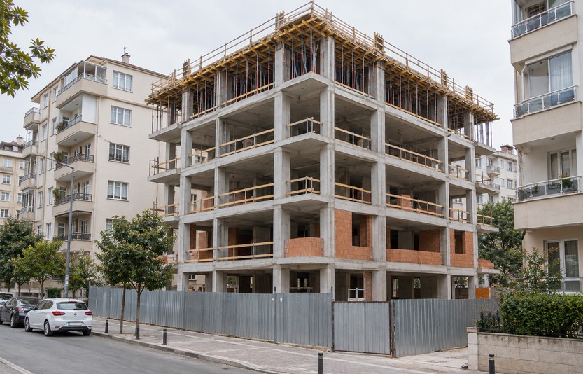 Kentsel dönüşümde konut mahallesi içinde yeni betonarme binanın yeniden yapım sürecini gösteren temsili görsel